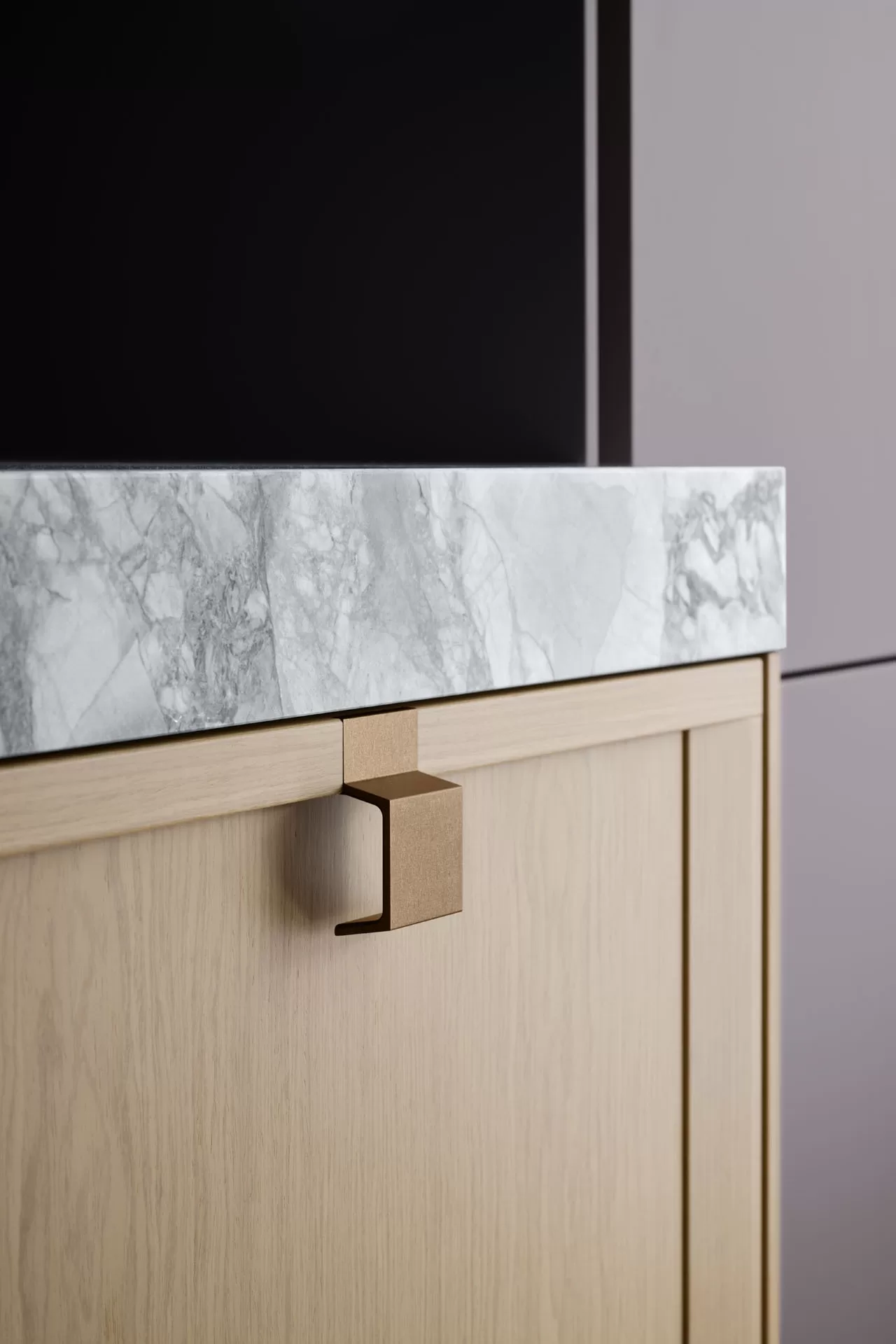 Detail of a SieMatic MONDIAL kitchen featuring natural stone, wood veneer, and a bronze handle