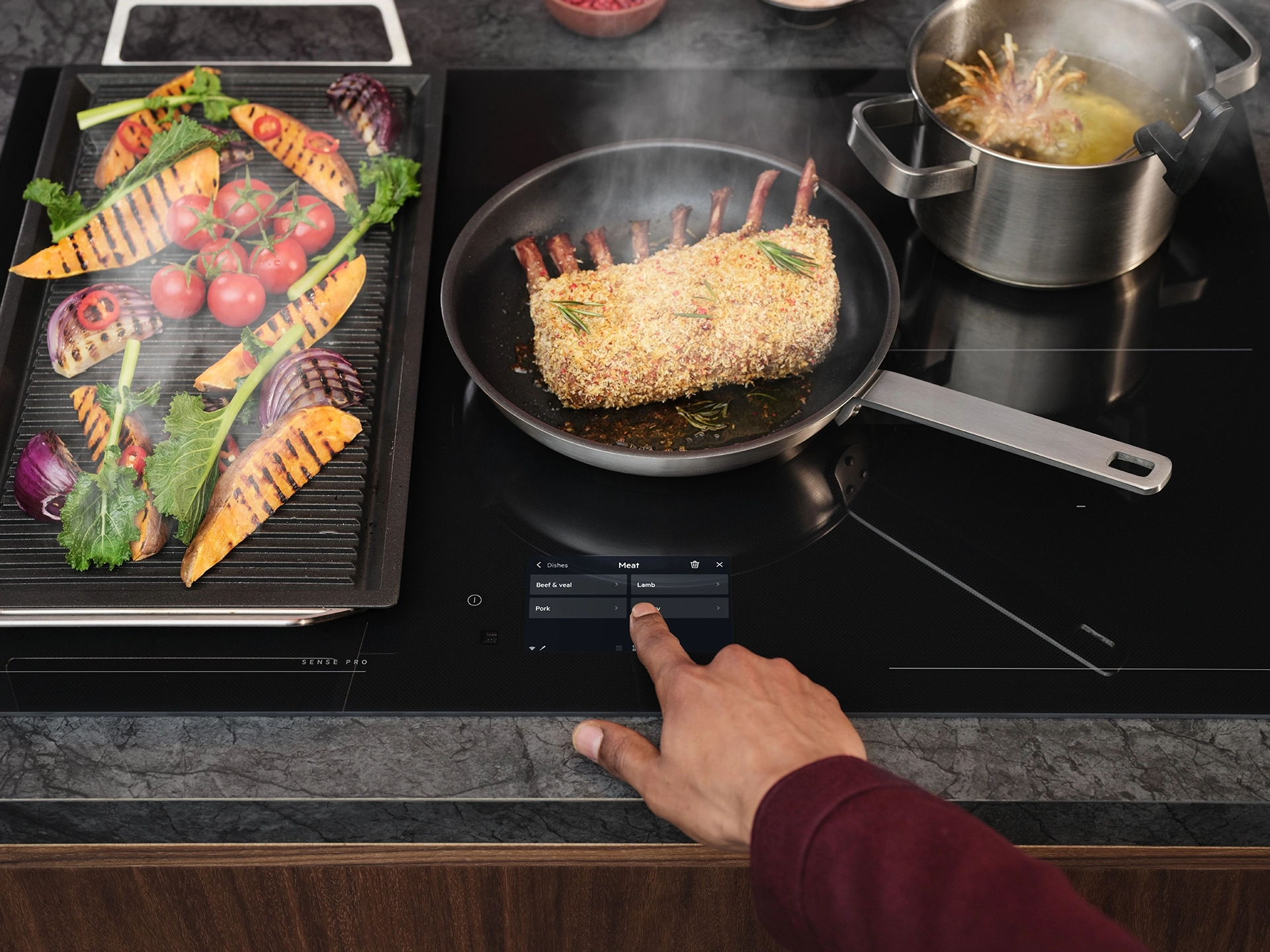 AEG SensePro inductiekookplaat met digitale kookassistentie waarop vlees, gegrilde groenten en een pan worden bereid
