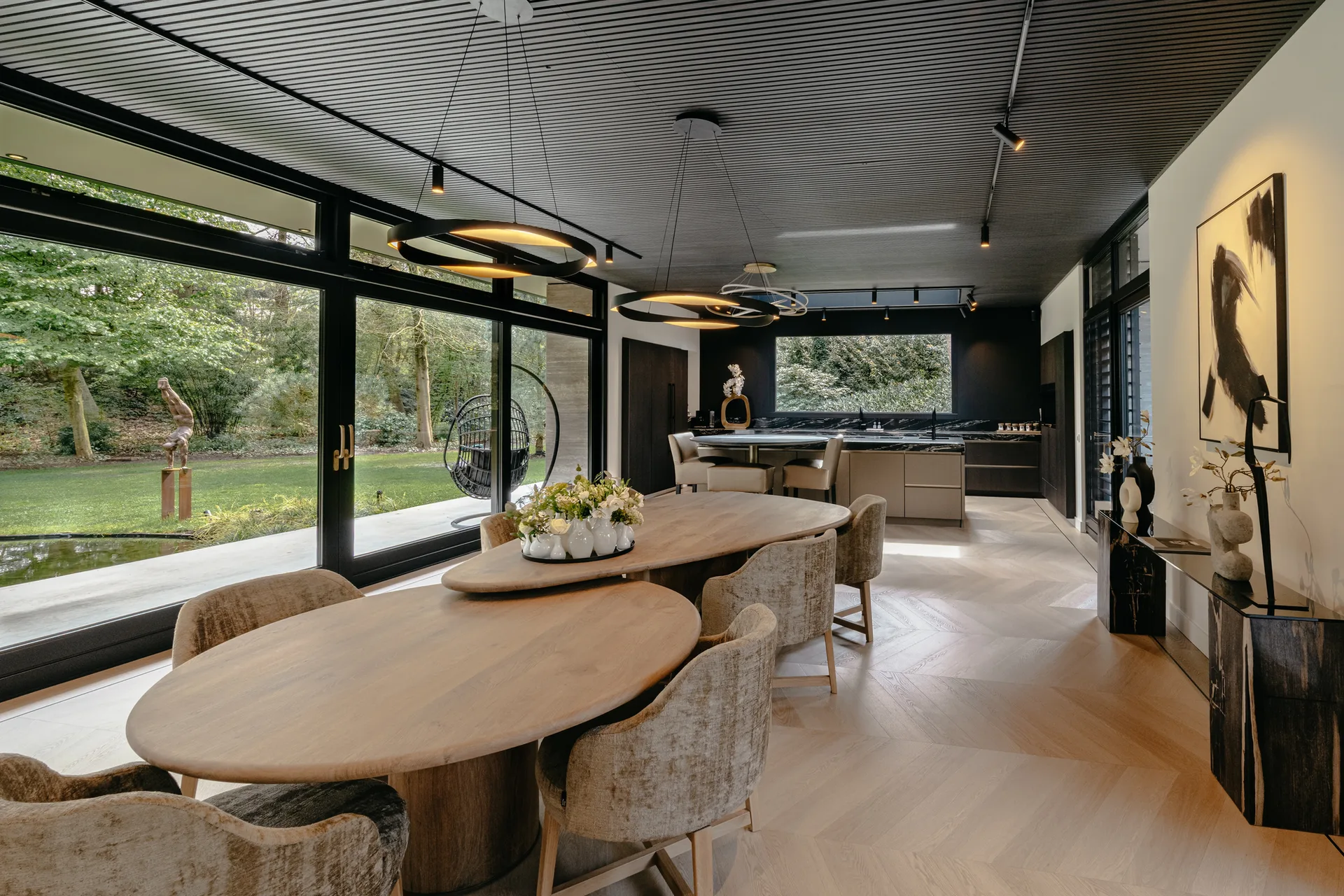 SieMatic open woonkeuken met kookeiland, grote eettafel en uitzicht op de tuin.