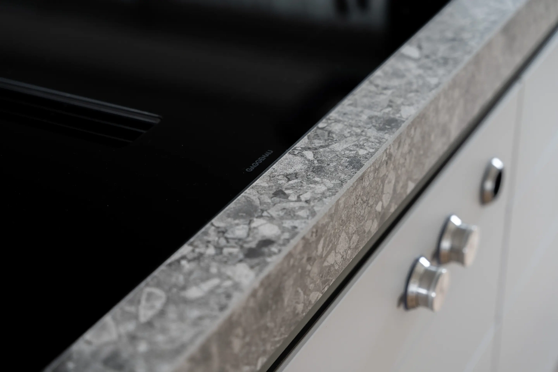 Detail van het natuurstenen werkblad in een chique witte SieMatic Classic keuken.