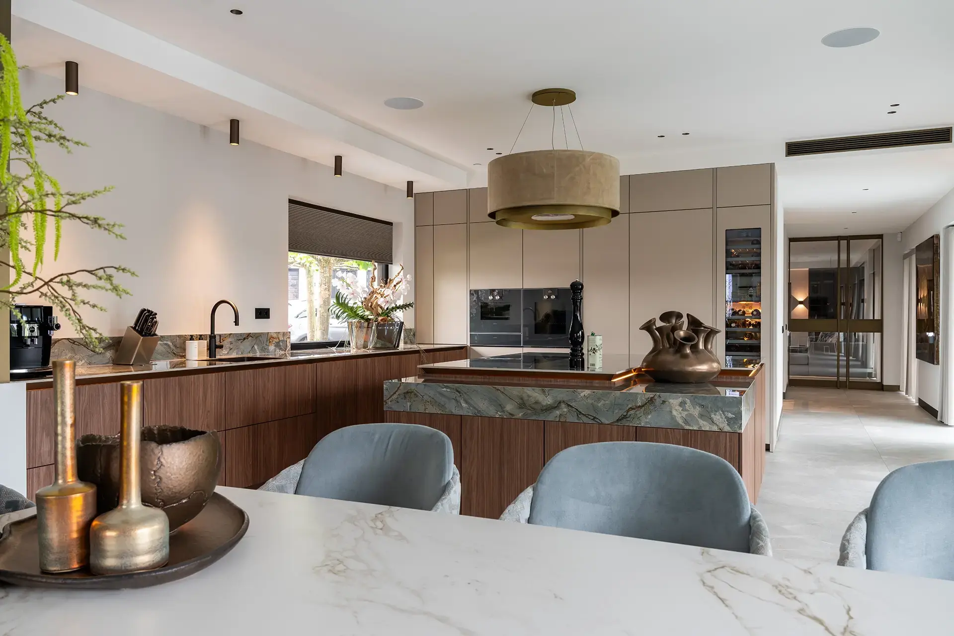 SieMatic woonkeuken met kookeiland, houtfineer en natuurstenen werkblad.
