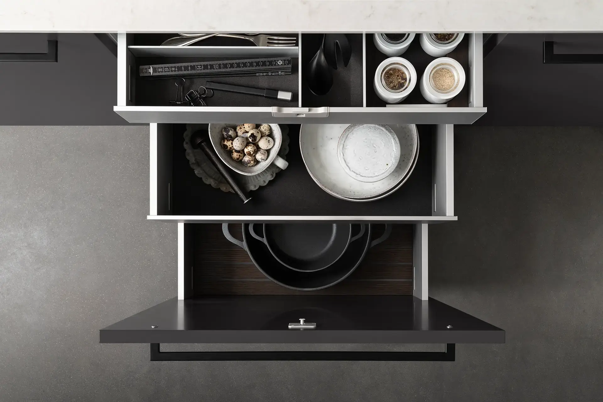 SieMatic GripDeck lade-indeling met georganiseerde opbergruimte voor servies, kruiden en kookgerei.