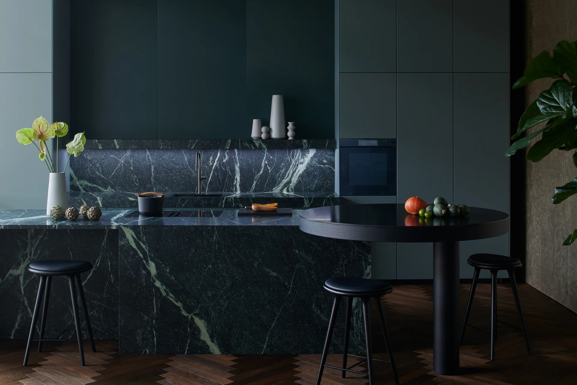 SieMatic Mondial keuken met natuurstenen kookeiland, ronde tafel en sculpturale vormgeving.
